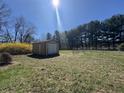 This image shows a backyard shed with a roll-up door, situated on a well-maintained grass lawn at 2115 Leonard Rd, Martinsville, IN 46151