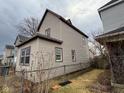 Side view of the two-story home with vinyl siding, framed windows, and a chain link fence at 413 W 8Th St, Muncie, IN 47302
