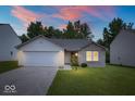 Charming single-story home featuring a brick facade, attached garage, and well-manicured lawn at dusk at 5842 Minden Dr, Indianapolis, IN 46221