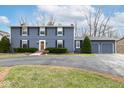 Blue home featuring a two-car garage, manicured shrubs, and a brick path to the front door at 619 Lawnwood Dr, Greenwood, IN 46142