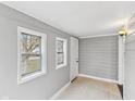 Cozy sunroom with gray painted walls, two windows, and white tiled flooring at 1241 Brandt Dr, Indianapolis, IN 46241