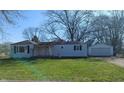 Exterior of a single-story home with an attached garage, front lawn and large trees at 318 Chester St, Anderson, IN 46012