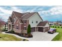 A well maintained two-story home with brick and green siding, an attached garage, and a pristine yard at 3240 Wildlife Trl, Zionsville, IN 46077