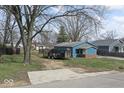 Blue home surrounded by trees; property includes grass and a driveway at 5006 W Naomi St, Indianapolis, IN 46241