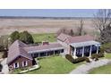 View of the spacious brick home with pillared porch and expansive surrounding fields at 7180 N State Road 42, Eminence, IN 46125