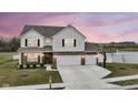 Charming home featuring a three-car garage, a basketball hoop, and a picturesque pond view at sunset at 836 Grassy Branch Dr, Indianapolis, IN 46239