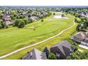 Scenic aerial view of a neighborhood with a golf course, a pond, and mature trees at 10844 Fairwoods Dr, Fishers, IN 46037