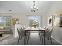 Open dining area with modern table, chandelier, and sliding door to backyard, adjacent to the living room at 12949 Shandon Ln, Fishers, IN 46038
