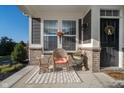Inviting front porch featuring a cozy wicker chair, side table, and decorative potted plants by the front door at 17346 Haxby Ln, Westfield, IN 46074