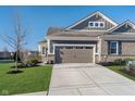 A two-car garage is framed by fresh landscaping and verdant green grass under a brilliant blue sky at 17346 Haxby Ln, Westfield, IN 46074