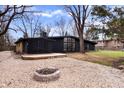 Backyard view showcasing a fire pit and patio area of a stone-accented home with large trees at 24 Thornhurst Dr, Carmel, IN 46032