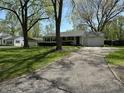Cozy single-Gathering home featuring a paved driveway leading to an attached garage and lush greenery at 2843 Canterbury Ln, Indianapolis, IN 46220