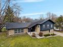 Aerial view of charming two-story home with unique stone and wood siding, a well-manicured lawn, concrete walkway at 3244 Devereaux Dr, Indianapolis, IN 46228