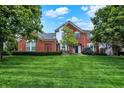 Beautiful brick home featuring lush green lawn, mature landscaping, and inviting front entrance at 6110 Tanana Dr, Carmel, IN 46033