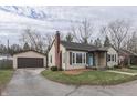 Exterior view of a charming home with a detached garage and well-maintained lawn at 631 E 86Th St, Indianapolis, IN 46240
