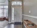 Bright foyer with a white front door, sidelights, transom window, hardwood floors, and neutral wall paint at 834 Bristle Lake Dr, Brownsburg, IN 46112