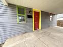 Close-up of a house's front porch with a red front door, colorful trim and gray siding at 980 Edgemont Ave, Indianapolis, IN 46208