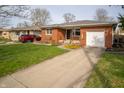 Charming brick home showcasing a well-manicured lawn and a concrete driveway leading to a garage at 1019 N Lesley Ave, Indianapolis, IN 46219