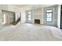 Unfinished living room area featuring a fireplace, large windows and staircase to the upper floor at 20598 Chatham Creek Dr, Westfield, IN 46074