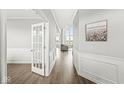 Bright hallway featuring hardwood floors, white wainscoting, and an open doorway leading to the living area at 4763 Denton Dr, Zionsville, IN 46077