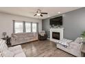 Comfortable living room with a fireplace, hardwood flooring, ceiling fan, and large windows at 5607 Regency Dr, Columbus, IN 47203