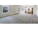 Bright and spacious living room with carpet flooring, neutral walls, and a view of the adjacent kitchen area at 733 Keepsake Run, Greenwood, IN 46143
