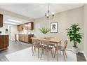 Well-lit dining area features a modern chandelier, a wood table, and a view of the kitchen at 7607 Farm View E Cir, Indianapolis, IN 46256