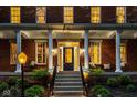 Inviting front porch with stately columns, seating, brick walkway, and manicured landscaping at 12897 Queens Troop, Carmel, IN 46032