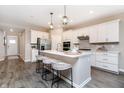 Beautiful kitchen with white cabinets, stainless appliances, island with bar stools and modern light fixtures at 17220 Cole Evans Dr, Noblesville, IN 46060