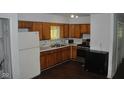 Kitchen with wood cabinets, laminate counters, white appliances, and dark flooring at 2194 N Riley Ave, Indianapolis, IN 46218