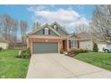 Inviting brick home featuring a lush green lawn, tidy landscaping, and an attached two-car garage at 3444 Windy Knoll Ln, Carmel, IN 46074