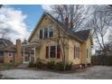 View of yellow two-story home featuring front porch, and gravel driveway at 5915 Lowell Ave, Indianapolis, IN 46219