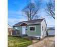 View of a cozy single-story home with light green siding and a detached garage at 621 Melvenia St, Indianapolis, IN 46219