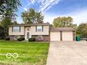 Split level home features a large manicured lawn, mature trees, and an attached two-car garage at 1402 Hornaday Rd, Brownsburg, IN 46112