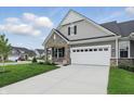 View of the home from the driveway, showcasing the garage, stone facade, and well-maintained landscaping at 16955 Cole Evans Dr, Noblesville, IN 46060
