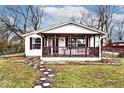A cozy one-story house featuring a covered porch with burgundy trim and a stepping stone path at 33 W Mill St, New Palestine, IN 46163