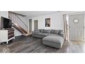 Modern living room with gray sofa, wood floors, staircase, and a stylish front door at 4814 Lynton Ct, Indianapolis, IN 46254
