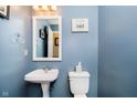 Cozy half-bathroom featuring stylish blue paint, a pedestal sink, and classic fixtures at 6134 Chadsworth Way, Lawrence, IN 46236