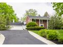 Inviting brick home featuring an attached garage, long driveway, and lush greenery at 650 Forest Blvd, Indianapolis, IN 46240