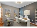 Modern office with a white desk, accent wall, shelves, and two windows offering natural light at 8259 Plumwood Ln, Indianapolis, IN 46256