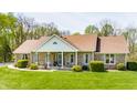 Attractive single-story brick home with a covered front porch, surrounded by greenery, on a sunny day at 8654 N Baltimore Rd, Monrovia, IN 46157