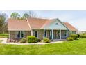 A single-story brick home showcases a classic design with a welcoming front porch and lush green lawn at 8654 N Baltimore Rd, Monrovia, IN 46157