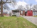 A brick home with front porch and a large, red barn style outbuilding in the backyard at 1237 E Pleasant Run Pkwy S Dr, Indianapolis, IN 46203