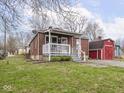 View of a brick home showing the front yard, red barn style outbuilding, and mature trees at 1237 E Pleasant Run Pkwy S Dr, Indianapolis, IN 46203