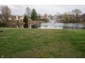 Backyard view of a tranquil pond with a fountain, complemented by green grass and a Canadian goose at 143 Tracy Ridge Blvd, Whiteland, IN 46184