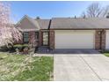 Charming brick home featuring an attached two-car garage, a well-manicured lawn, and a lovely flower bed at 1739 Wellesley Commons # 48A, Indianapolis, IN 46219