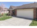 Charming brick home featuring an attached two-car garage, a well-manicured lawn, and a lovely flower bed at 1739 Wellesley Commons # 48A, Indianapolis, IN 46219