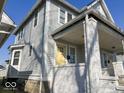 Exterior shot of a house with light gray wood siding and a covered porch with a yellow front door at 2148 Singleton St, Indianapolis, IN 46203