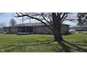 Large backyard with a spacious lawn, shaded by a mature tree and a screened-in patio at 3002 W 53Rd St, Anderson, IN 46011