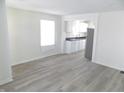 Open-concept living area showcasing the gray laminate flooring, kitchen, and window at 3323 E 36Th St, Indianapolis, IN 46218